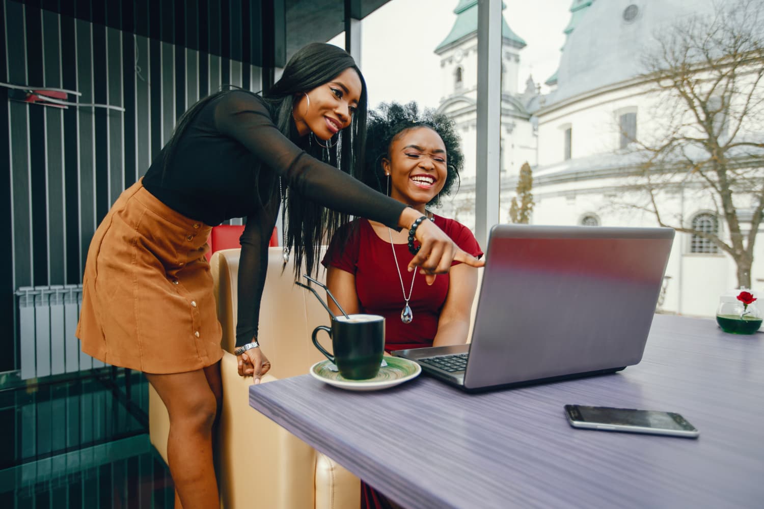 Two Nigerian businesswomen celebrating a closed deal at the laptop