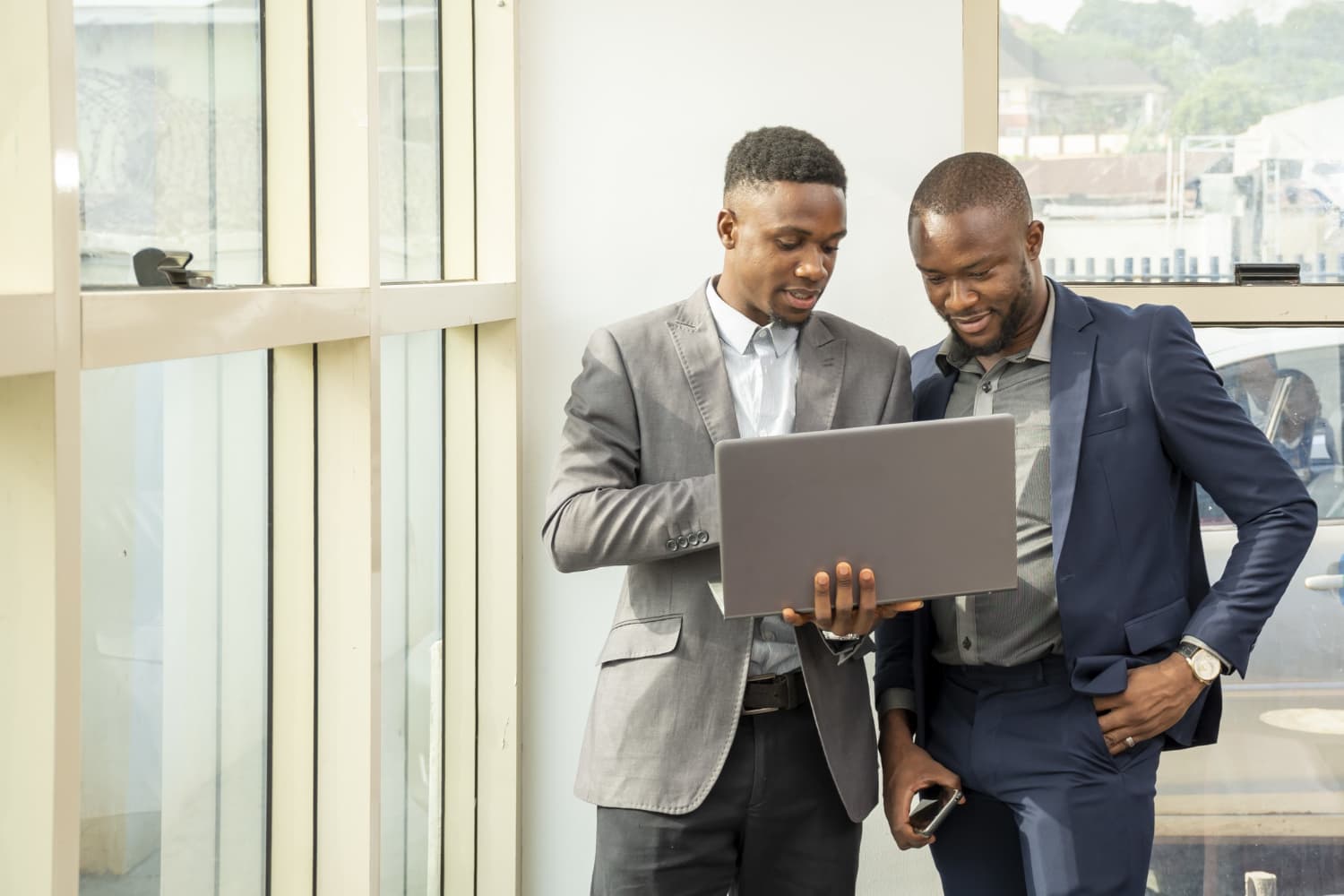 Two Nigerian businessmen reviewing financials together on a laptop