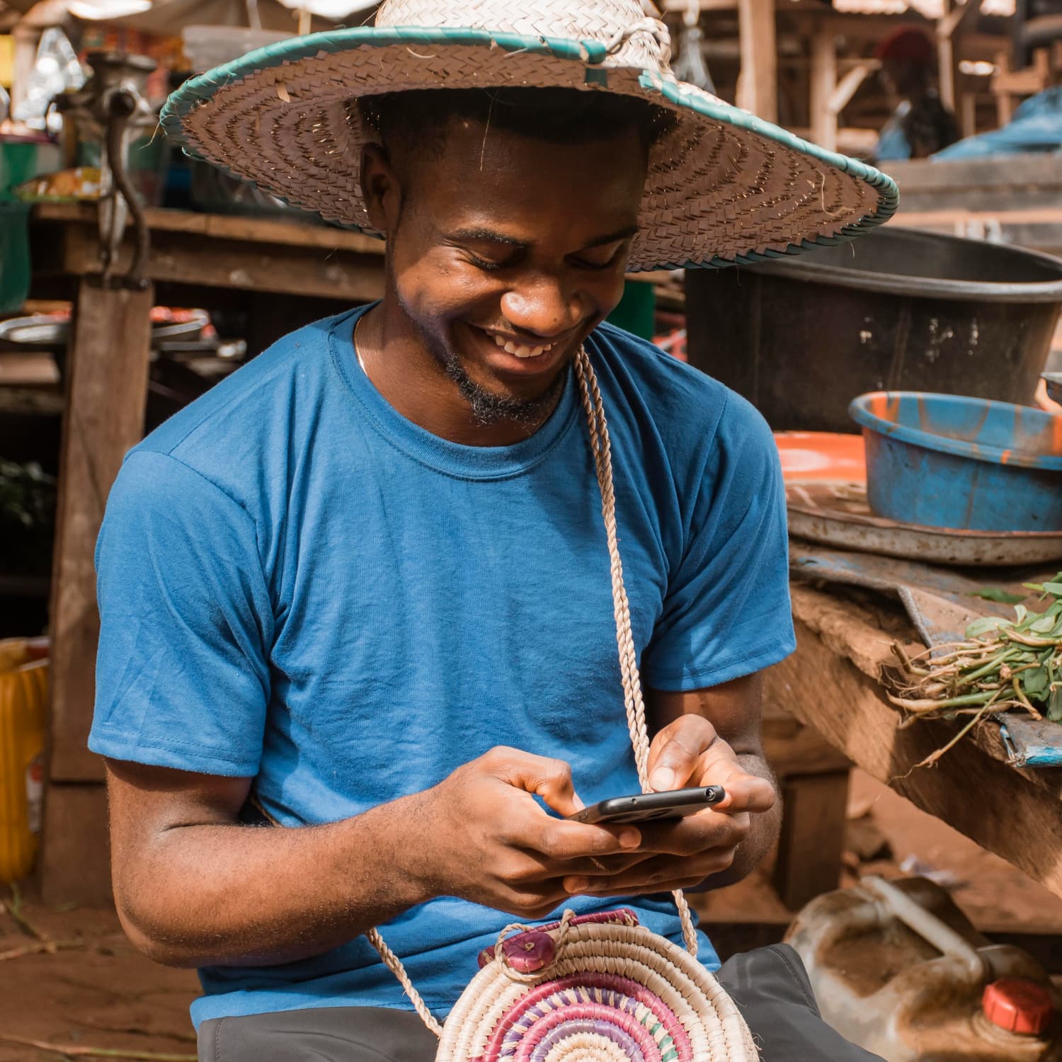 Nigerian market trader using his phone to manage stock at the market